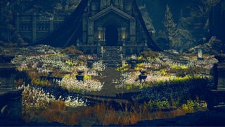 An establishing shot of the interior of the Ruins Of Unte in Elden Ring: Shadow Of The Erdtree, with a bed of colourful flowers between the camera and the altar in the centre of the ruins.